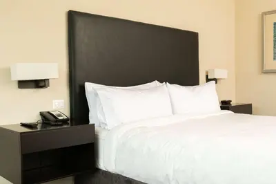 a bedroom with a bed with a black headboard and a phone at Hilton San Salvador in San Salvador
