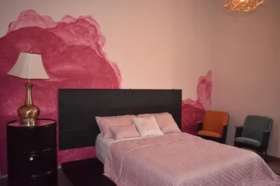 a bedroom with a bed and a pink wall at Hostal Sole in Santa Ana