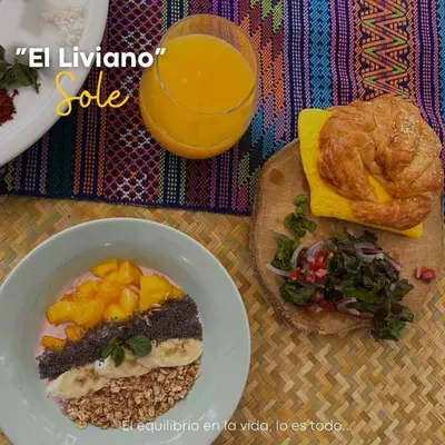 a table with a bowl of food and a glass of orange juice at Hostal Sole in Santa Ana