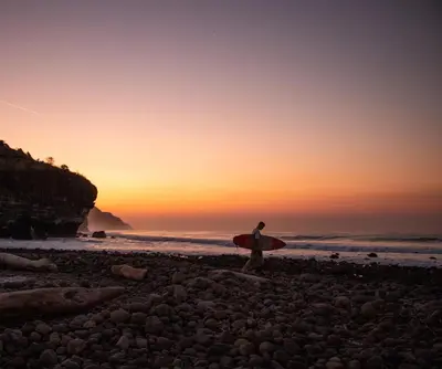 a man standing on a beach holding a surfboard at Mizata By Antiresort in Santa María Mizata