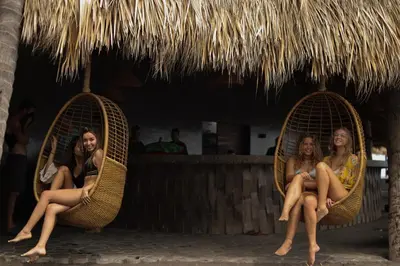three women sitting in wicker chairs under a straw umbrella at Mizata By Antiresort in Santa María Mizata