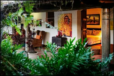 a living room with a bed and some plants at Los Almendros de San Lorenzo in Suchitoto