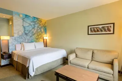 a hotel room with a bed and a couch at Courtyard by Marriott San Salvador in San Salvador