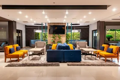 a lobby with a blue couch and yellow chairs at Courtyard by Marriott San Salvador in San Salvador
