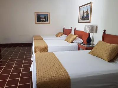 a hotel room with three beds and a lamp at Hotel Villa Serena Escalon in San Salvador