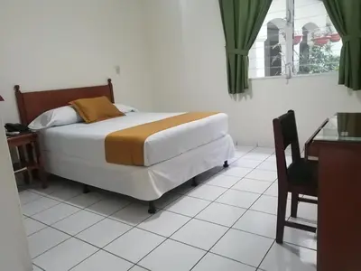 a bedroom with a bed and a table and a chair at Hotel Villa Serena San Benito in San Salvador
