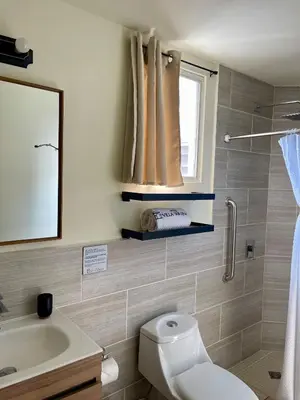 a bathroom with a toilet and a sink and a window at Hotel Villa Serena San Benito in San Salvador