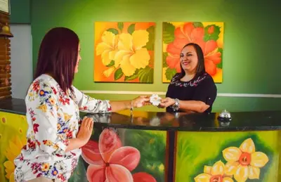 two women are shaking hands in front of a counter at Eco Hotel Mariscal in San Salvador