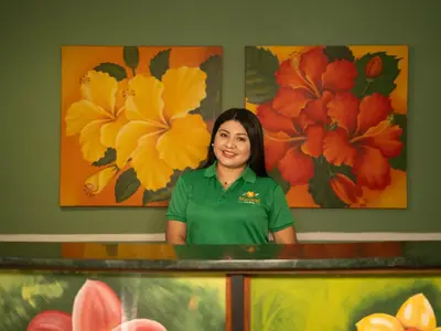 a woman standing in front of a counter with paintings at Eco Hotel Mariscal in San Salvador