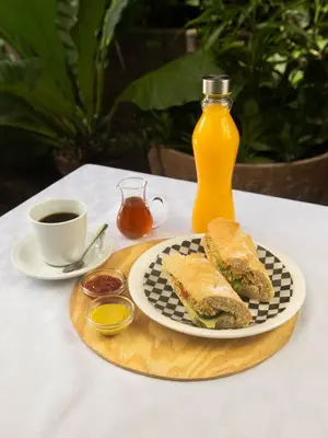 a sandwich and a cup of coffee and a bottle of orange juice at Eco Hotel Mariscal in San Salvador