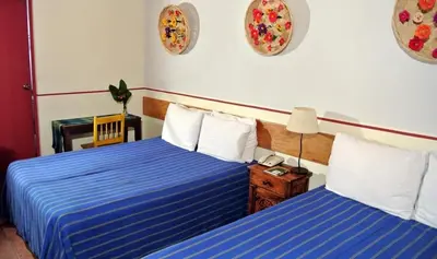 a bedroom with two beds with blue sheets and a table at Arbol de Fuego Eco-hotel in San Salvador