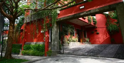 a red building with a red wall and a tree at Arbol de Fuego Eco-hotel in San Salvador