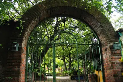 an iron gate in a brick wall with trees behind it at La Posada de Suchitlan in Suchitoto