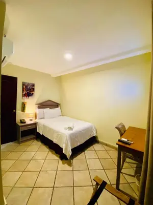 a bedroom with a bed and a table and a desk at Morrison Hotel San Salvador in San Salvador