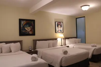 a hotel room with three beds and a painting on the wall at Morrison Hotel San Salvador in San Salvador