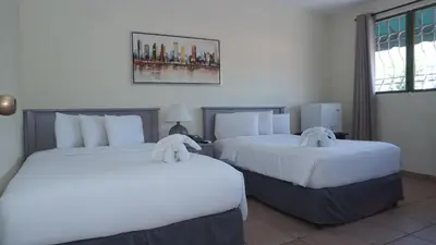 two beds in a hotel room with white sheets at Morrison Hotel San Salvador in San Salvador
