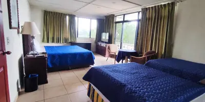 a hotel room with two beds and a desk and a table at Hotel Mediterraneo Plaza in San Salvador