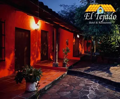 a red building with two potted plants in front of it at El Tejado in Suchitoto