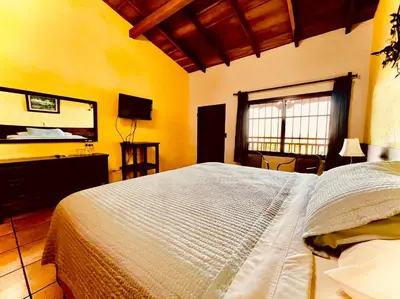 a bedroom with a large bed and a television at El Tejado in Suchitoto