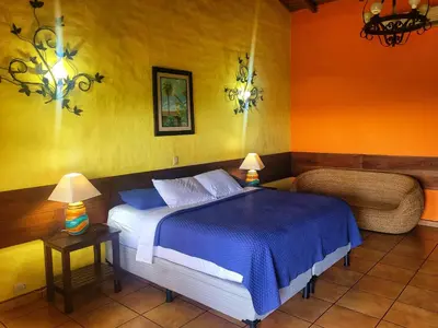a bedroom with a blue bed and a chair at El Tejado in Suchitoto
