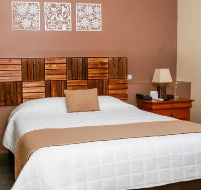 a bedroom with a large white bed with wooden panels at Las Magnolias Hotel Boutique in San Salvador