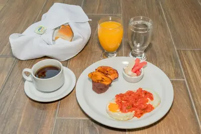 a plate of breakfast food and a cup of coffee and orange juice at Las Magnolias Hotel Boutique in San Salvador