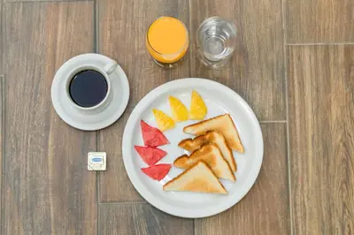 a plate of bread and fruit on a table with a cup of coffee at Las Magnolias Hotel Boutique in San Salvador