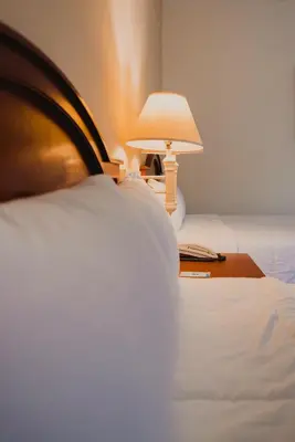 a bed with a table with a lamp on it at Hotel Mirador Plaza in San Salvador