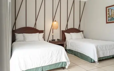 two beds in a room with white sheets at Hotel Mirador Plaza in San Salvador