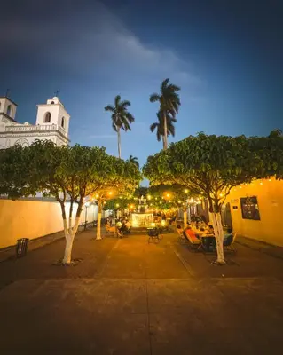 a street with trees and chairs and a building at La Casa de Mamapán Hotel Colonial Ahuachapan in Ahuachapán
