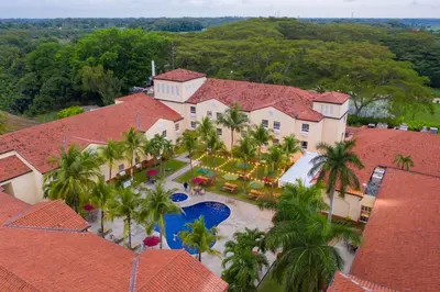 an aerial view of a resort with a pool and palm trees at Quality Hotel Real Aeropuerto San Salvador in San Luis