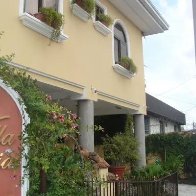 a yellow house with potted plants on the windows at Hotel Villa Florencia Zona Rosa in San Salvador