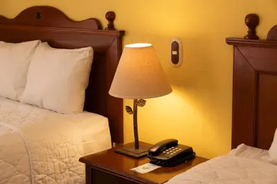 a lamp on a table next to a bed with a phone at Hotel Villa Terra in San Salvador