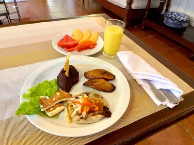 a table with two plates of food and a glass of orange juice at Hotel Villa Terra in San Salvador