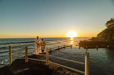 a couple standing on a pier watching the sunset at Hotel Los Farallones in La Libertad
