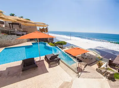 a swimming pool with orange umbrellas and the beach at Hotel Los Farallones in La Libertad