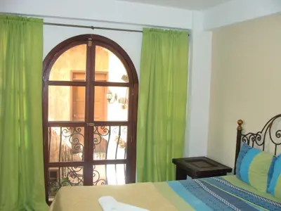 a bedroom with a bed and a window with green curtains at Hotel Villa Florencia Centro Histórico in San Salvador
