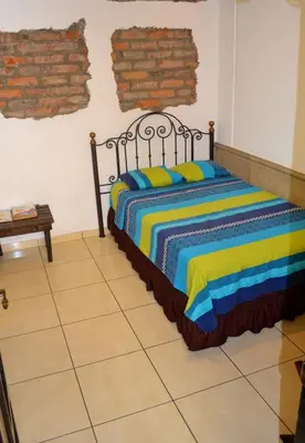 a bedroom with a bed with a colorful striped blanket at Hotel Villa Florencia Centro Histórico in San Salvador