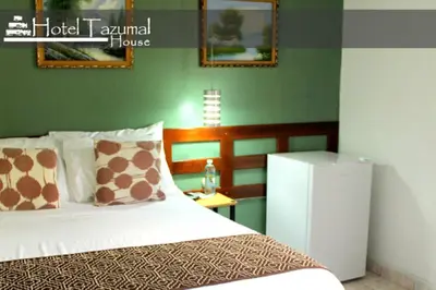 a bedroom with a bed and a small refrigerator at Hotel Tazumal House in San Salvador