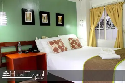 a hotel room with a bed and a night stand at Hotel Tazumal House in San Salvador