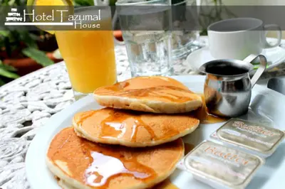 three pancakes on a plate on a table with a drink at Hotel Tazumal House in San Salvador