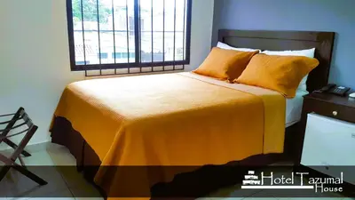a bedroom with a bed with yellow sheets and a window at Hotel Tazumal House in San Salvador