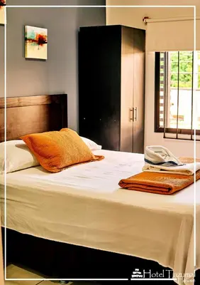 a bed with white sheets and orange pillows on it at Hotel Tazumal House in San Salvador