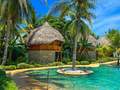 a resort with a pool and palm trees at Hotel Tortuga Village in La Herradura