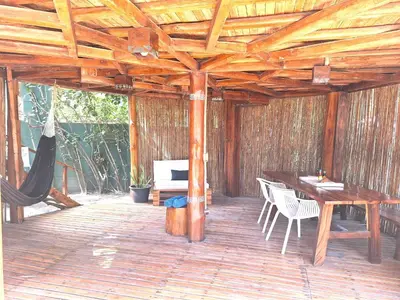 a wooden patio with a hammock and a table and chairs at Hotel Tortuga Village in La Herradura