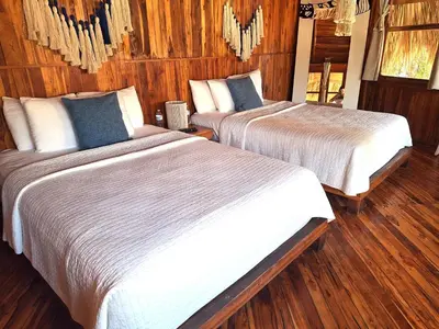 two beds in a room with wooden walls and wood floors at Hotel Tortuga Village in La Herradura