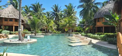 a pool at a resort with chairs and palm trees at Hotel Tortuga Village in La Herradura