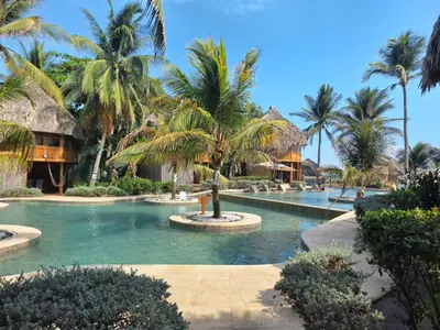 a resort swimming pool with palm trees and houses at Hotel Tortuga Village in La Herradura