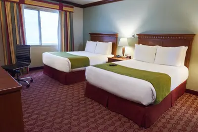 a hotel room with two beds and a desk at Suites las Palmas, Hotel & Apartments. in San Salvador
