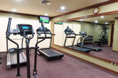 a gym with tread machines in front of a mirror at Suites las Palmas, Hotel & Apartments. in San Salvador